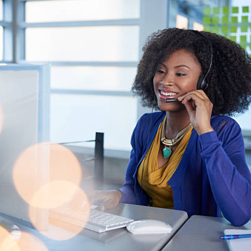 help-urhometutor Friendly african american casual call center emplyee working at a desktop computer in a modern withe office